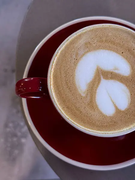  Bir kapuçinonun yakın plan fotoğrafı, fincan tabağındaki seramik bardakta latte ile birlikte. Sütlü sütlü sıcak kahve..