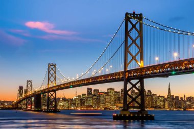 Downtow City silüeti ve ünlü Golden Gate Köprüsü, Kaliforniya 'da güneş batarken San Francisco