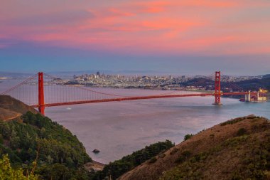 Downtow City silüeti ve ünlü Golden Gate Köprüsü, Kaliforniya 'da güneş batarken San Francisco