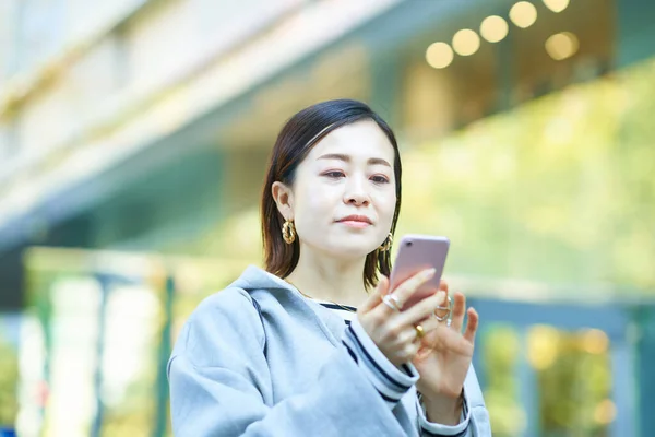 屋外のスマートフォン画面を見ている女性 — ストック写真