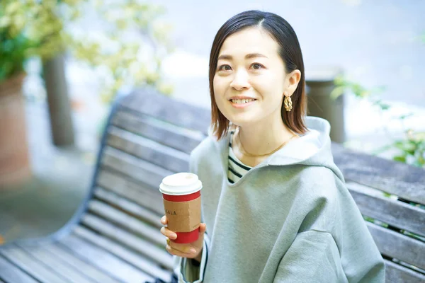 リラックスした表情で屋外でコーヒーを飲む女性 — ストック写真