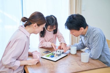 Ayrılmış bir evin modeline bakarken tartışan bir aile.