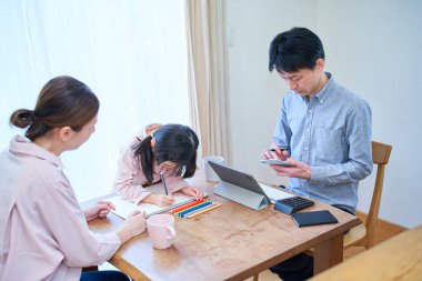 Anne ve kız oynuyor, resim yapıyor ve baba odada çalışıyor.