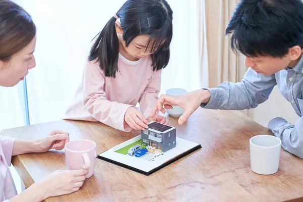 戸建住宅の模型を見ながら話し合う家族 — ストック写真