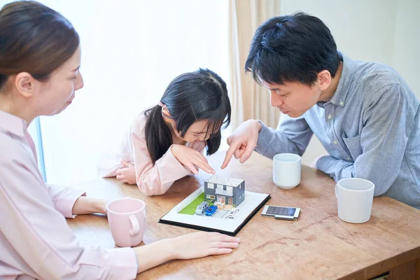 戸建住宅の模型を見ながら話し合う家族 — ストック写真