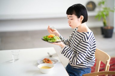 Genç bir kadın evde yemek yiyor.