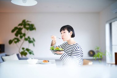 Genç bir kadın evde yemek yiyor.