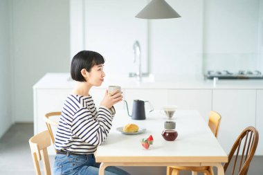 Genç bayan odada kahve içiyor.