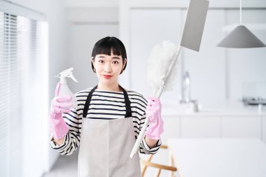 Odada temizlik aletleri olan genç bir kadın.