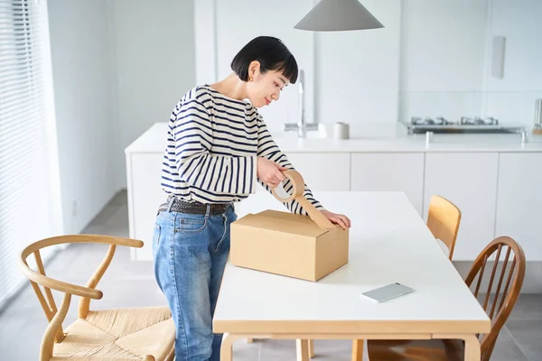 stock image Young woman packing a cardboard box in the room