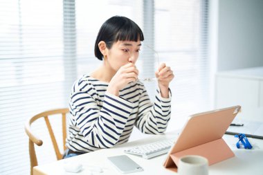 Gözlük takan ve masasında çalışan genç bir kadın.