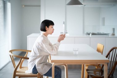 Odada akıllı telefon kullanan genç bir kadın.