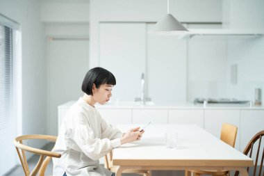 Odada akıllı telefon kullanan genç bir kadın.