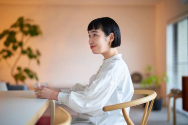 Sakin odada su içen genç bir kadın.