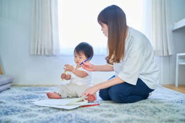 Genç anne ve çocuk resimle oynuyorlar.