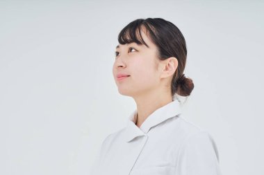 Young woman wearing a white coat indoors and white background
