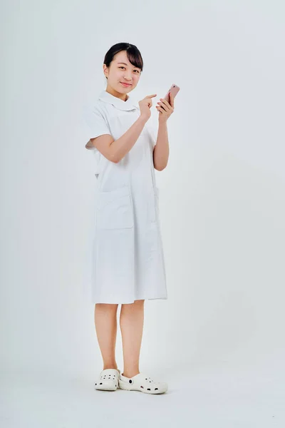 Beyaz Önlüklü Akıllı Telefon Beyaz Arka Plan Kullanan Bir Kadın — Stok fotoğraf