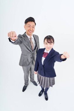 A man and a high school girl in a suit doing a guts pose and white background
