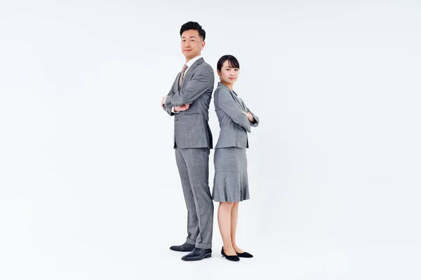 Man and woman in suits standing back to back and white background