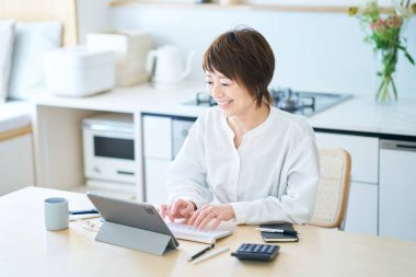 Odanın mutfağında internetten iletişim kuran bir kadın.