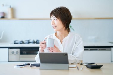 Bir kadın evde çalışırken bir kupayla mola veriyor.