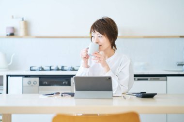 Bir kadın evde çalışırken bir kupayla mola veriyor.