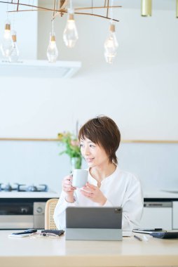 Bir kadın evde çalışırken bir kupayla mola veriyor.