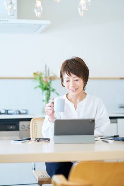 Odanın mutfağında internetten iletişim kuran bir kadın.