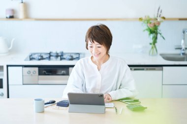 Odanın mutfağında internetten iletişim kuran bir kadın.