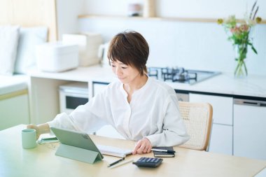 Odanın mutfağında internetten iletişim kuran bir kadın.