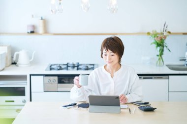 Bir kadın evde çalışırken bir kupayla mola veriyor.