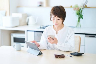 Mutfak odasında akıllı telefon kullanan bir kadın.