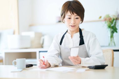 Önlüklü bir kadın odada makbuzları kontrol ediyor.