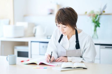 Önlüklü bir kadın mutfakta mesajla çalışıyor.