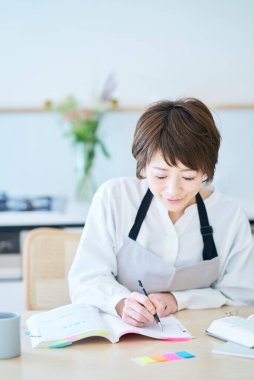 Önlüklü bir kadın mutfakta mesajla çalışıyor.