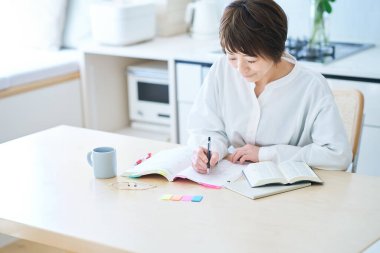 Otuzlarında bir kadın odada mesajla ders çalışıyor.