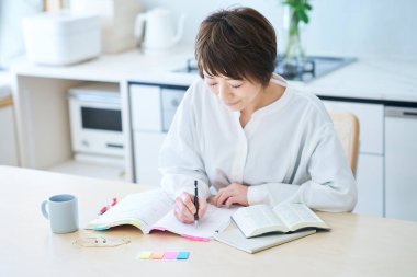 Otuzlarında bir kadın odada mesajla ders çalışıyor.