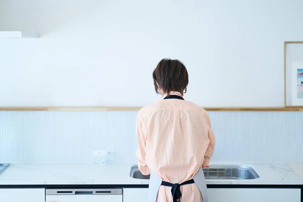 一个女人在厨房洗碗的背景图 — 图库照片