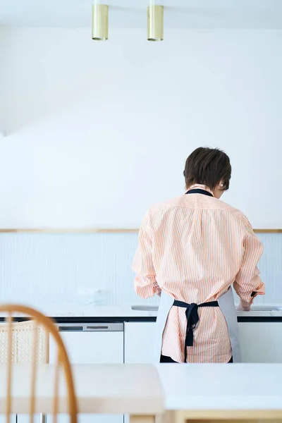 一个女人在厨房洗碗的背景图 — 图库照片