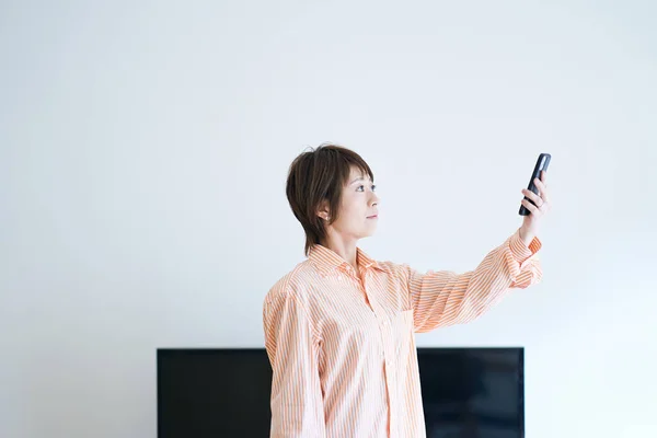 Uma Mulher Segurando Smartphone Dentro Casa — Fotografia de Stock
