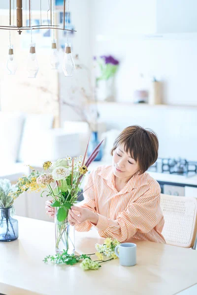 部屋に花瓶の花を配置する女性 — ストック写真