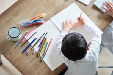 Odasında çalışan bir anne ve çizim yapan bir çocuk.