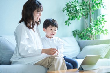 Anne ve çocuk kanepede oturup tabletin ekranına bakıyorlar.