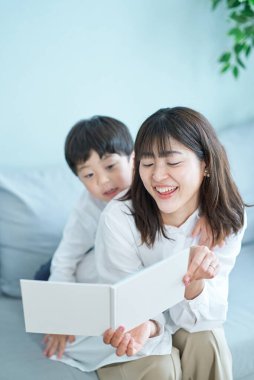 Anne ve çocuk kanepede oturup resim kitabı okuyorlar.