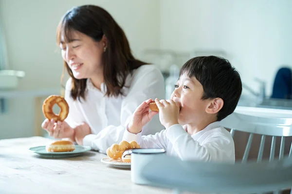 母親と息子は家でドーナツを食べて — ストック写真