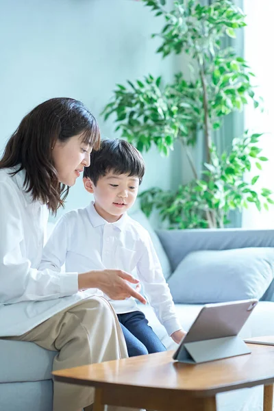 母亲和孩子坐在沙发上 看着平板电脑的屏幕 — 图库照片