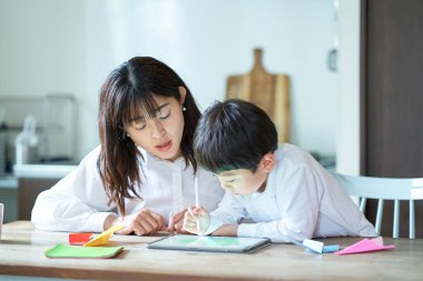 Anne ve çocuk odada bir tabletle oynuyorlar.