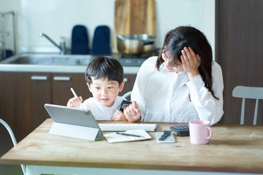Çocuğu tarafından rahatsız edilirken yanında çalışan yorgun bir anne.