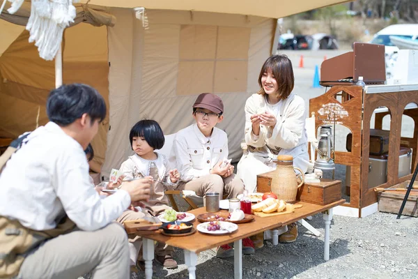 A family of five enjoying a meal at a campsite