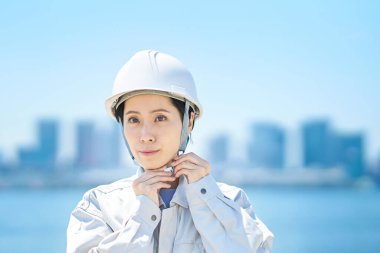 İş kıyafetleri giyen ve güzel bir günde kask takan bir kadın.